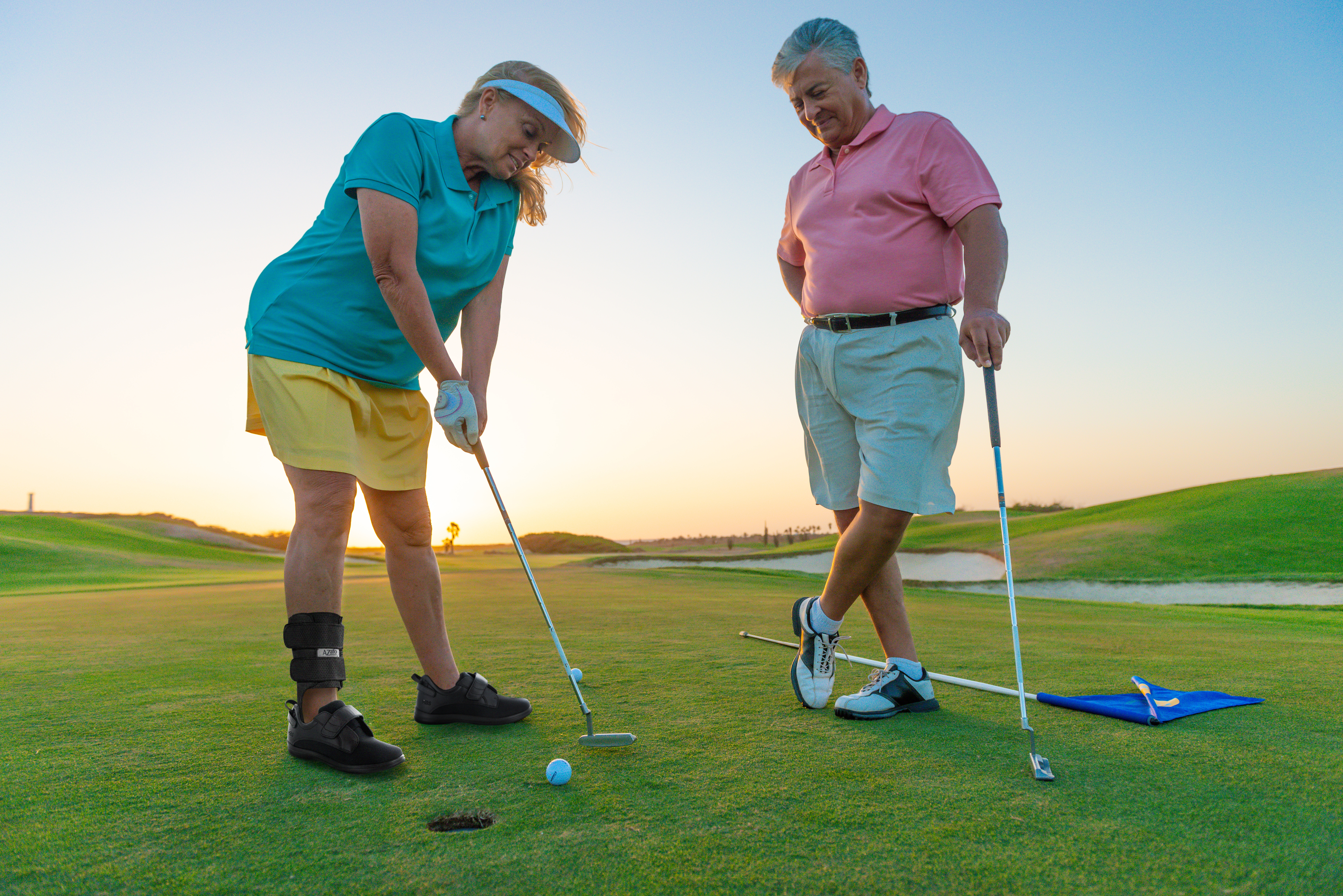 Coupe golfing outside. Woman is wearing ankle brace and Women's Balance Shoe (ABS) Black