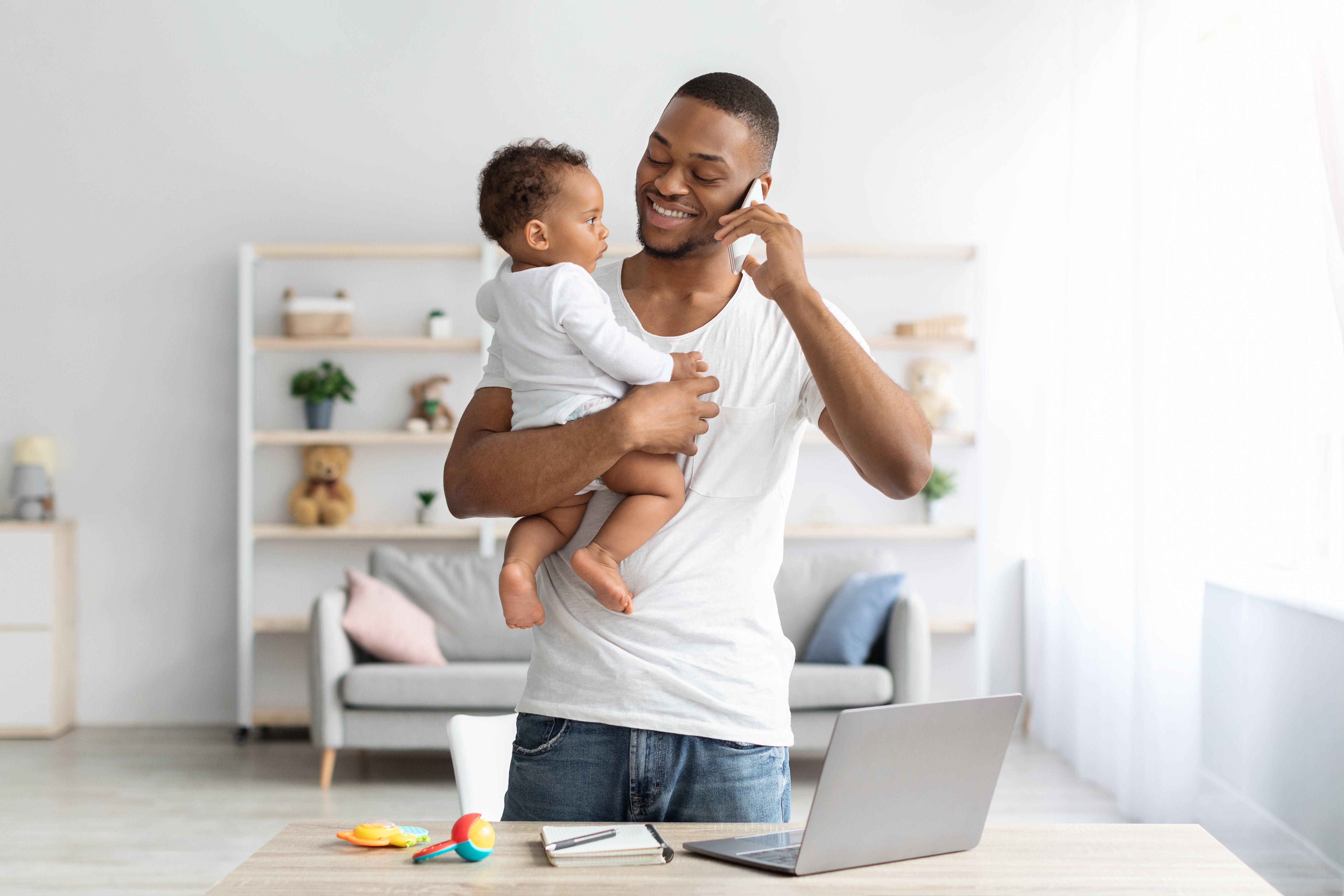 Father holding baby while on the phone.