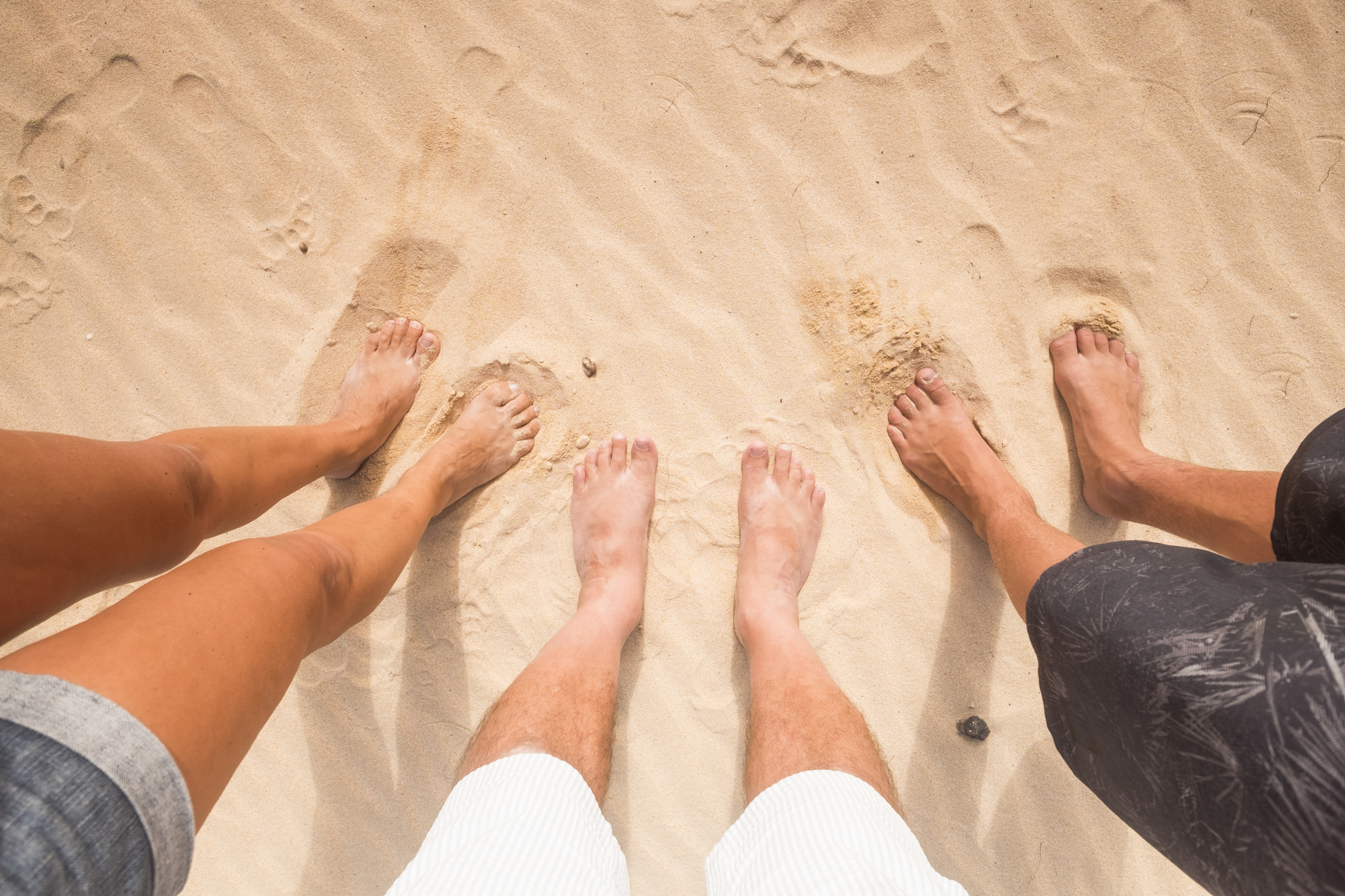 Three people different sex and age with the feet in the sand