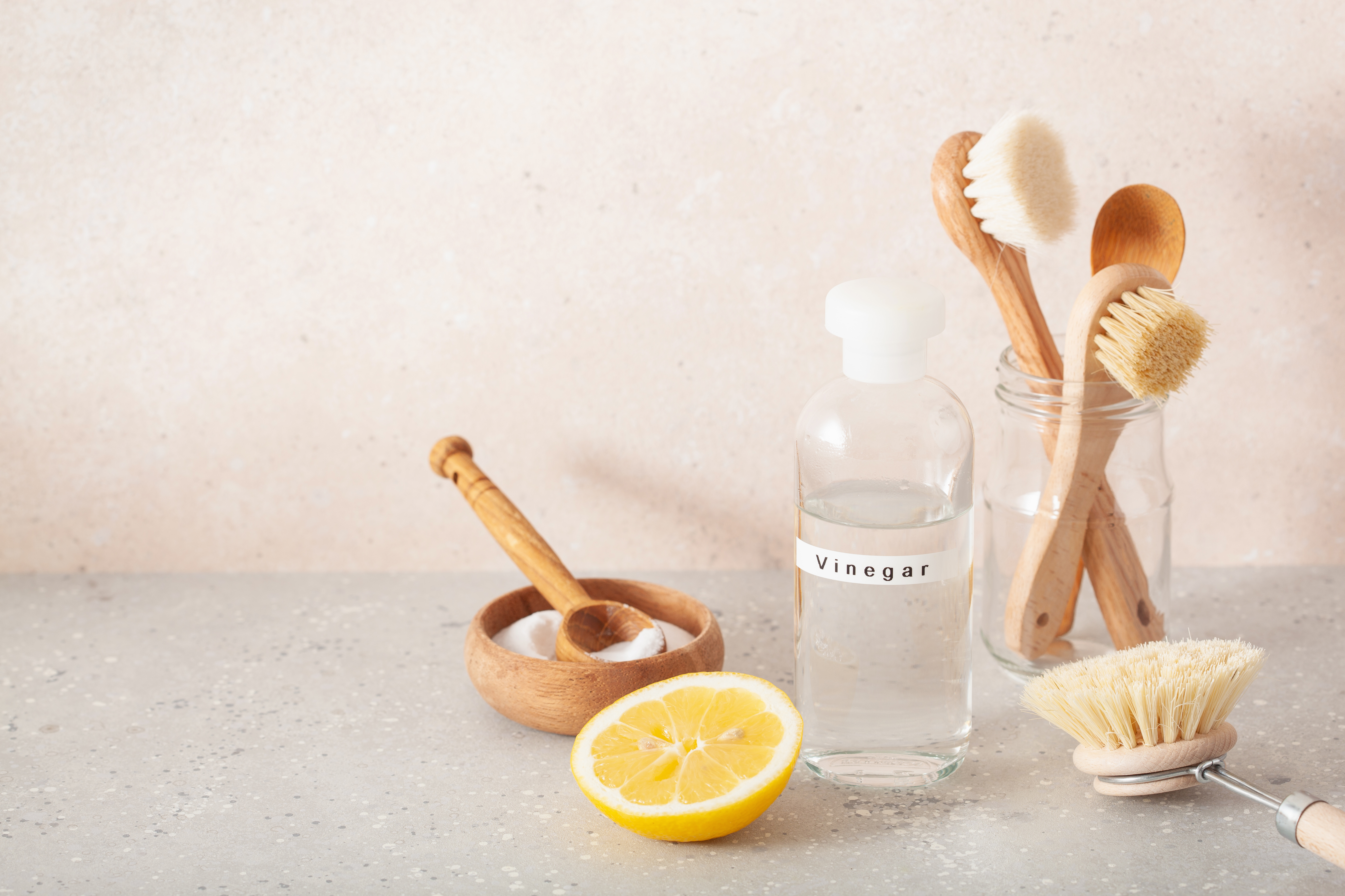 Close up of wooden brushes, lemon, baking soda, vinegar on table